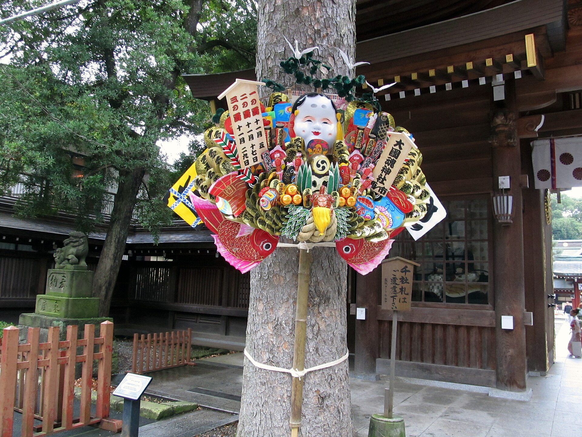 府中・大國魂神社の境内社、大鷲神社の大きな縁起熊手。おかめの面、鯛、小判で飾られている。写真：Fuchu / Wikimedia Commons / CC BY-SA 4.0（2024年11月2日撮影）