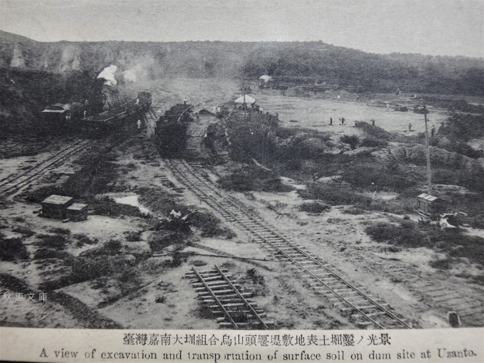 1920年代の絵はがき「臺灣嘉南大圳組合烏山頭堰堤敷地表土鑿光景」。むき出しの工事現場を線路と蒸気機関車が走る。撮影者不詳・秋惠文庫所蔵 / Wikimedia Commons / パブリックドメイン