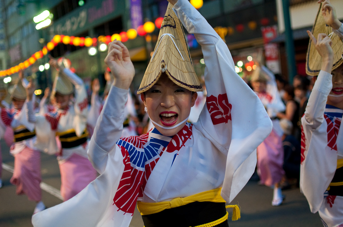 徳島の阿波おどりで、編み笠をかぶった女性の踊り手たちが、そろって手を上げて踊っている
