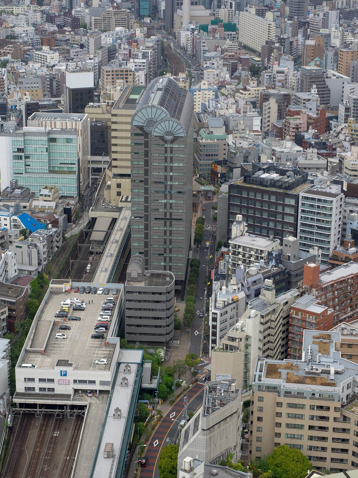 恵比寿駅を上から見下ろした様子。線路がアトレ恵比寿の駅ビルと屋上駐車場の下を通り、周りに恵比寿の街並みが広がる。写真：Ajay Suresh / Wikimedia Commons / CC BY 2.0（2018年4月14日撮影）