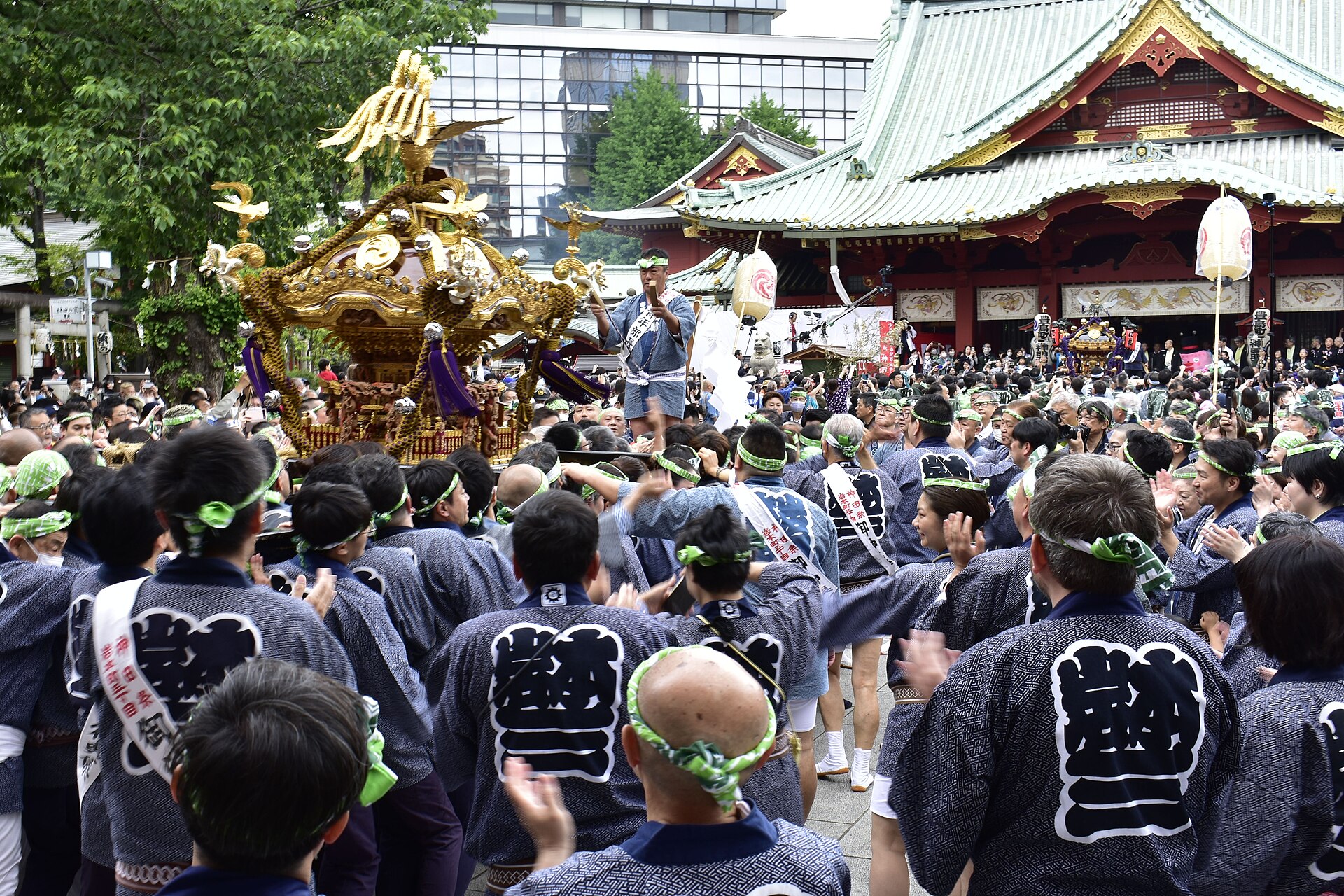Carriers in matching neighbourhood-association hanten coats and twisted headbands surround a golden mikoshi in the grounds of Kanda Myojin during the Kanda Matsuri. Photo: 江戸村のとくぞう (Edomura no Tokuzō) / Wikimedia Commons / CC BY-SA 4.0 (14 May 2023)